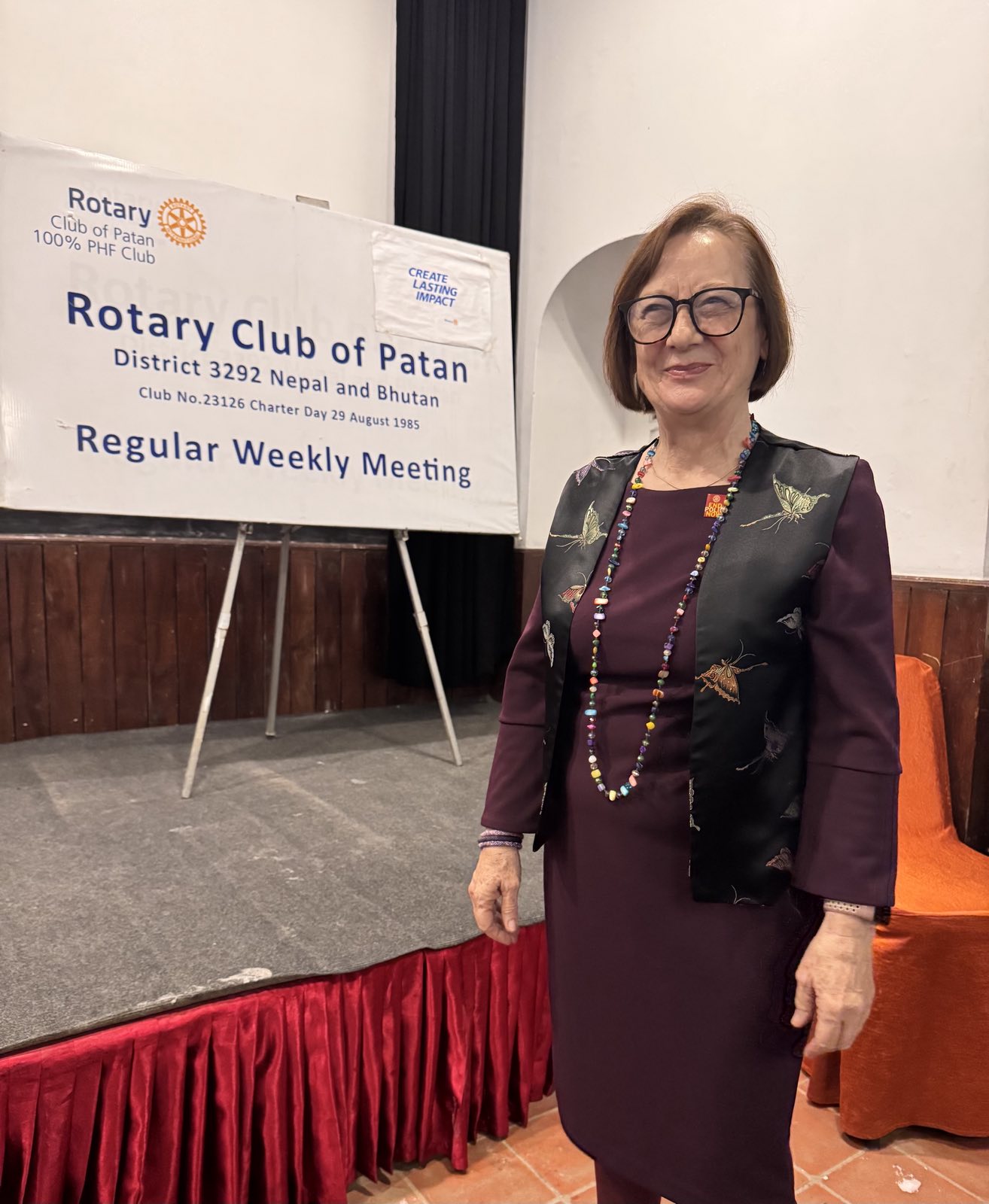A speaker beside the Rotary Club of Patan regular weekly meeting banner on World Polio Day.
